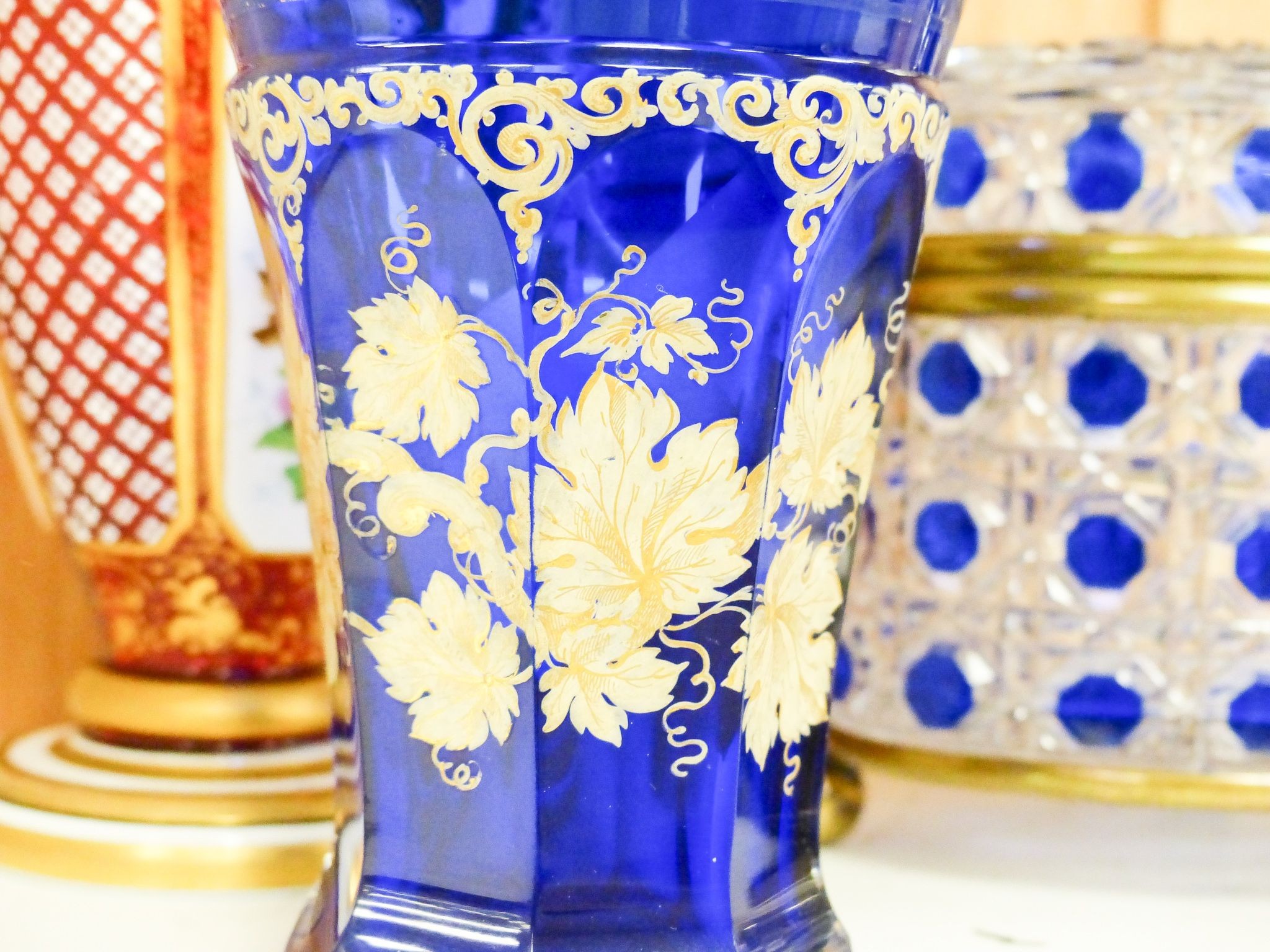 A 19th century Bohemian overlaid glass vase, 25.5cm, a similar gilded and enamelled beaker and two blue flashed hobnail glass biscuit boxes and covers